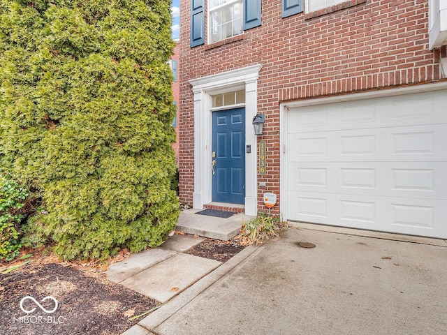 doorway to property with a garage and brick siding