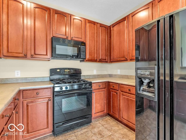 kitchen with brown cabinetry, light countertops, black appliances, and light tile patterned floors