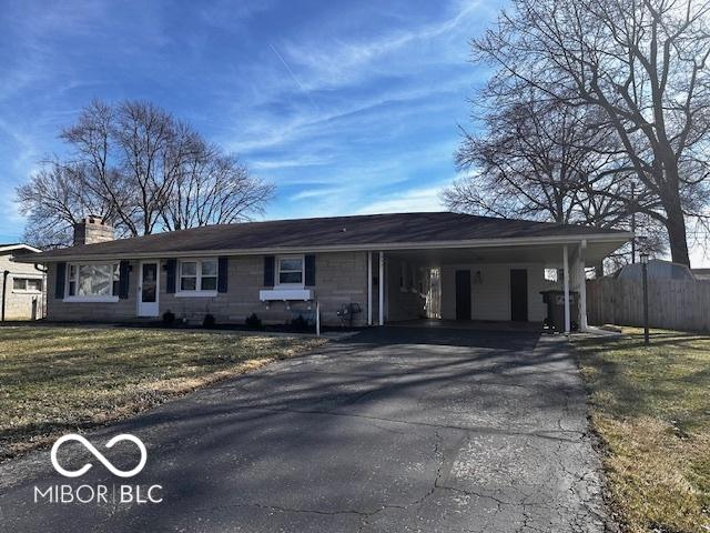 ranch-style house with a chimney, aphalt driveway, fence, a front lawn, and a carport