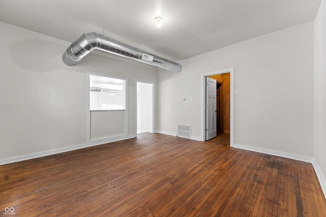 empty room featuring visible vents, baseboards, and dark wood-style flooring