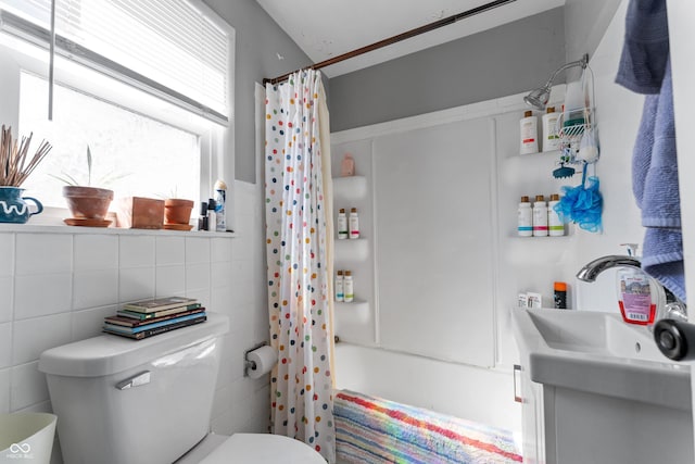 full bath featuring a sink, shower / bathtub combination with curtain, toilet, and tile walls