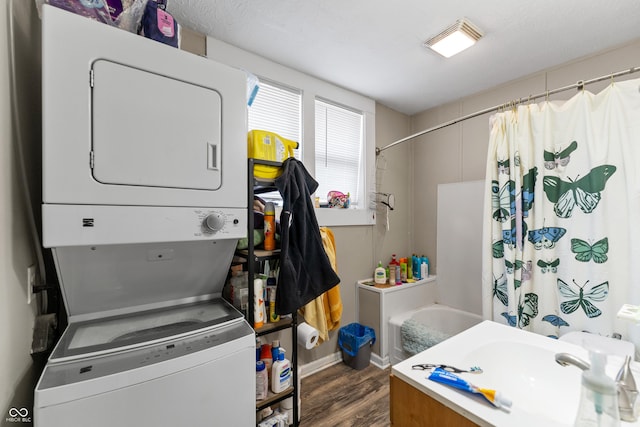 clothes washing area with dark wood finished floors, laundry area, and stacked washer / dryer