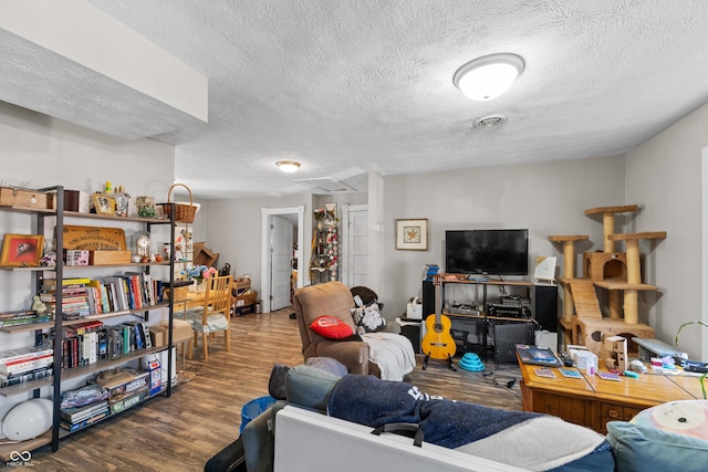 living area with wood finished floors, visible vents, and a textured ceiling