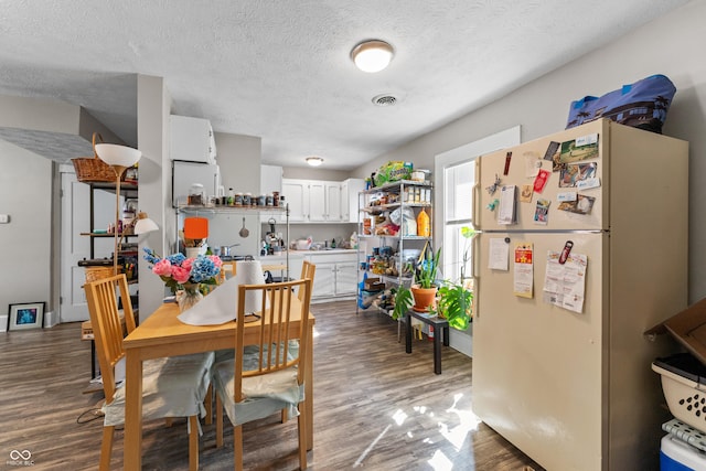 dining area with visible vents, a textured ceiling, and wood finished floors