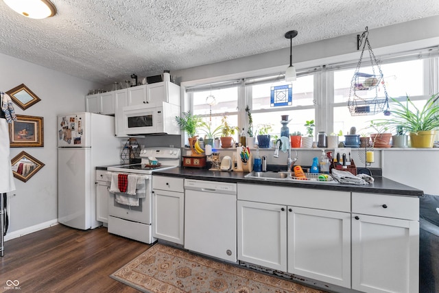 kitchen featuring dark countertops, a sink, white appliances, white cabinetry, and dark wood-style flooring