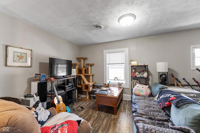 living area featuring visible vents, plenty of natural light, a textured ceiling, and wood finished floors