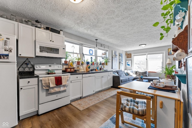 kitchen with white appliances, open floor plan, dark wood-type flooring, and white cabinets