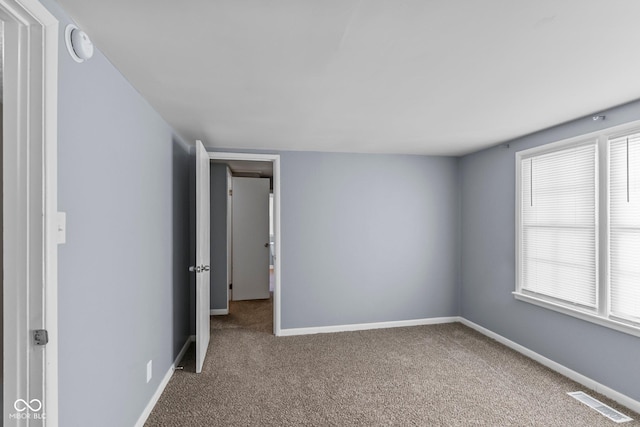 carpeted spare room with visible vents and baseboards