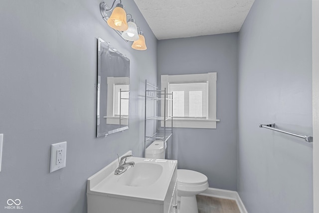 bathroom featuring a textured ceiling, toilet, wood finished floors, vanity, and baseboards