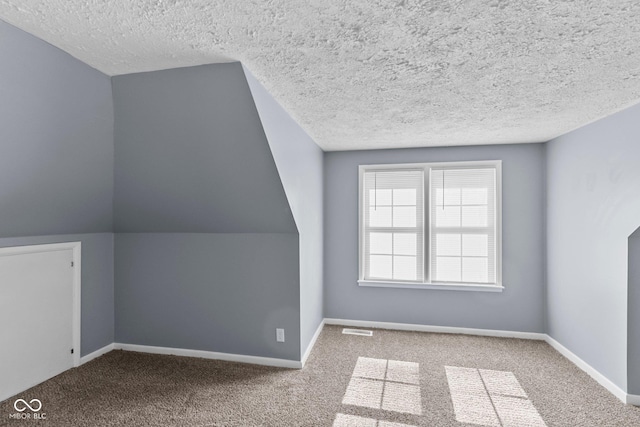 additional living space with carpet floors, baseboards, visible vents, and a textured ceiling