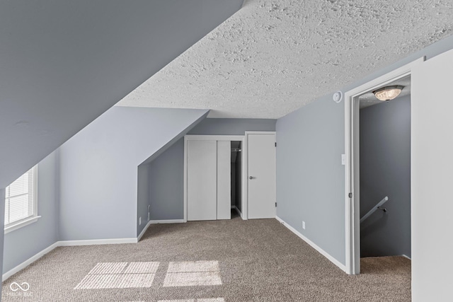 bonus room with a textured ceiling, carpet flooring, and baseboards