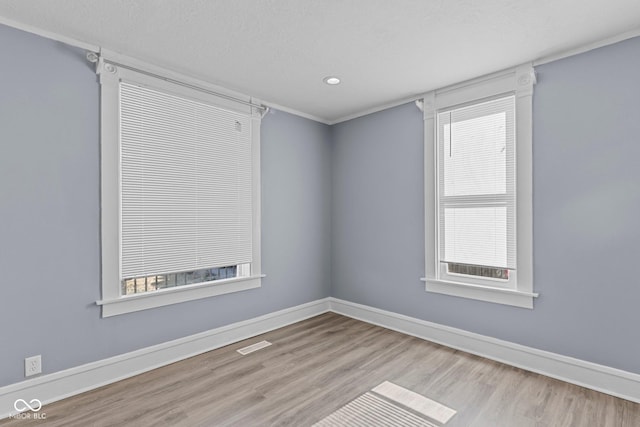 spare room featuring a healthy amount of sunlight, baseboards, and wood finished floors