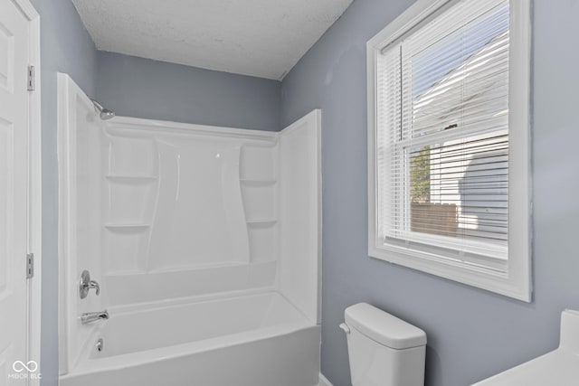 bathroom with a textured ceiling, bathtub / shower combination, and toilet