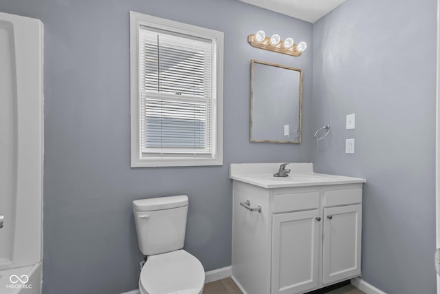 bathroom with toilet, vanity, and baseboards