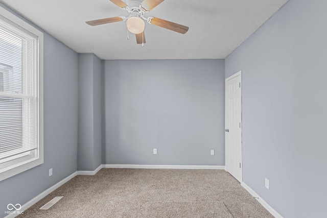 carpeted spare room with a ceiling fan, visible vents, and baseboards