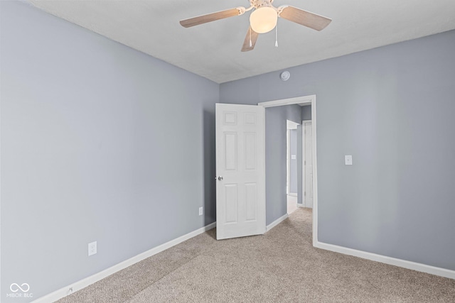 carpeted spare room with baseboards and a ceiling fan