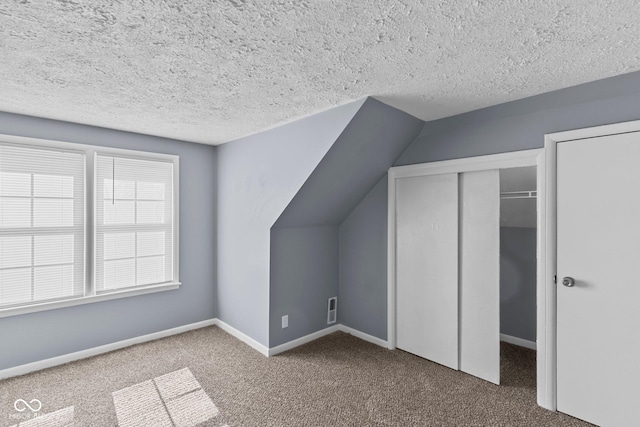 bonus room with lofted ceiling, visible vents, carpet flooring, a textured ceiling, and baseboards