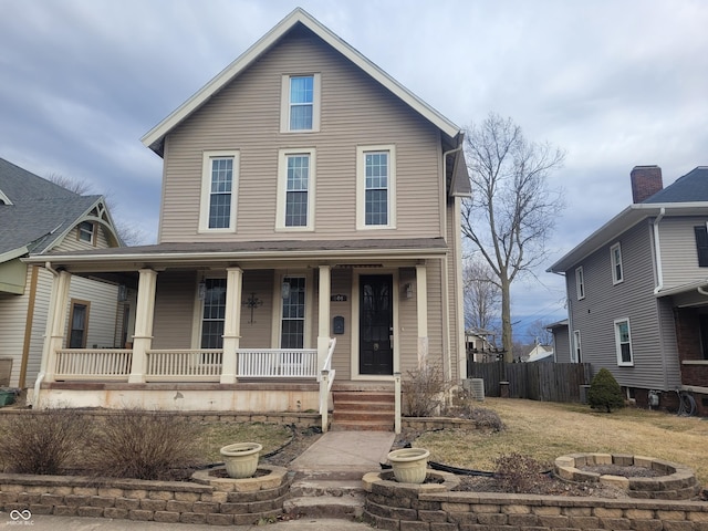 view of front of house featuring central air condition unit, a fire pit, fence, and covered porch