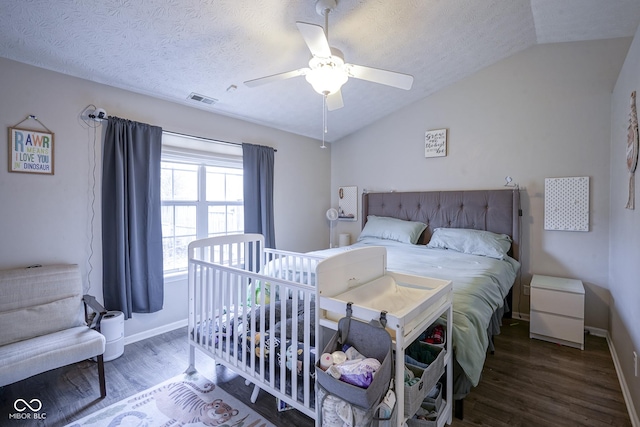 bedroom with visible vents, a textured ceiling, wood finished floors, ceiling fan, and vaulted ceiling