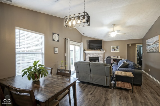 dining room featuring dark wood finished floors, a fireplace, baseboards, and vaulted ceiling