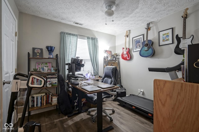 office area featuring ceiling fan, wood finished floors, visible vents, and a textured ceiling