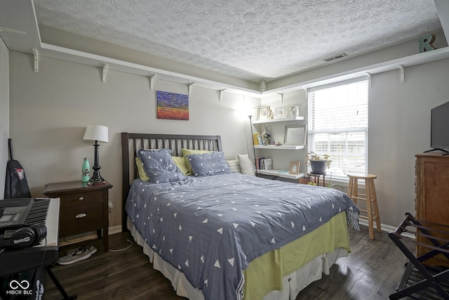 bedroom with baseboards, wood finished floors, visible vents, and a textured ceiling