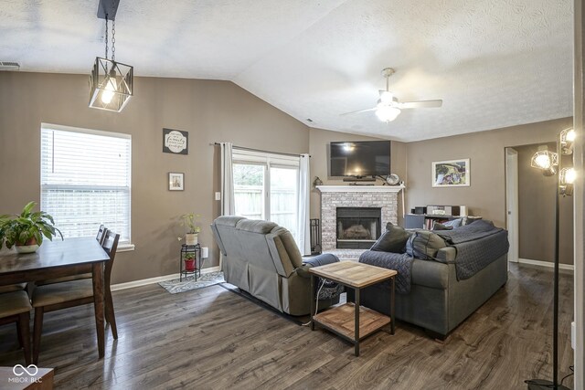 living area featuring lofted ceiling, a brick fireplace, dark wood-type flooring, and a textured ceiling