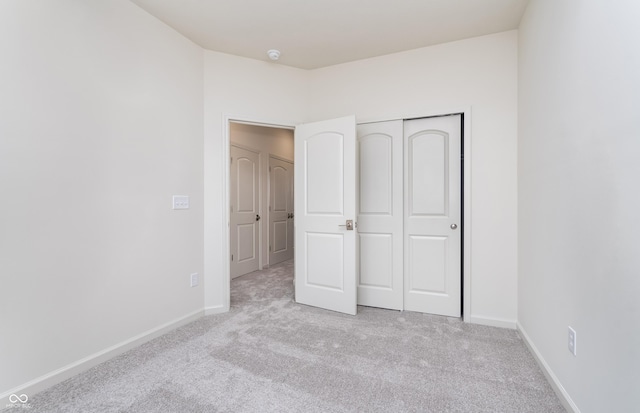 unfurnished bedroom featuring a closet, baseboards, and carpet flooring