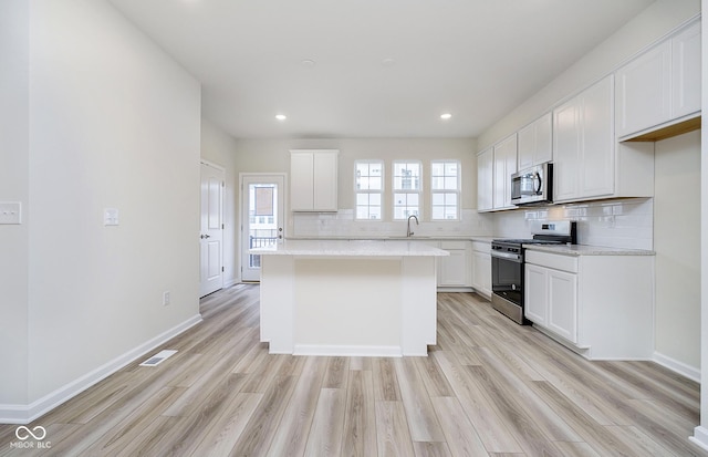 kitchen featuring tasteful backsplash, visible vents, light countertops, light wood-style flooring, and appliances with stainless steel finishes