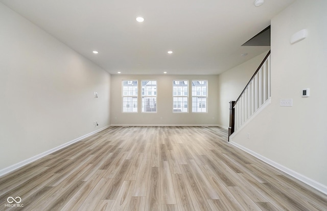 unfurnished living room with stairway, light wood-style flooring, recessed lighting, and baseboards