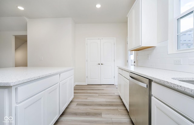 kitchen featuring light wood finished floors, dishwasher, light stone counters, decorative backsplash, and white cabinets