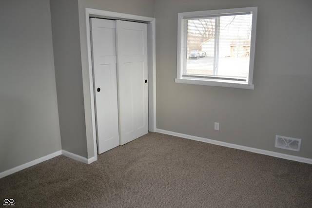 unfurnished bedroom featuring a closet, carpet flooring, visible vents, and baseboards