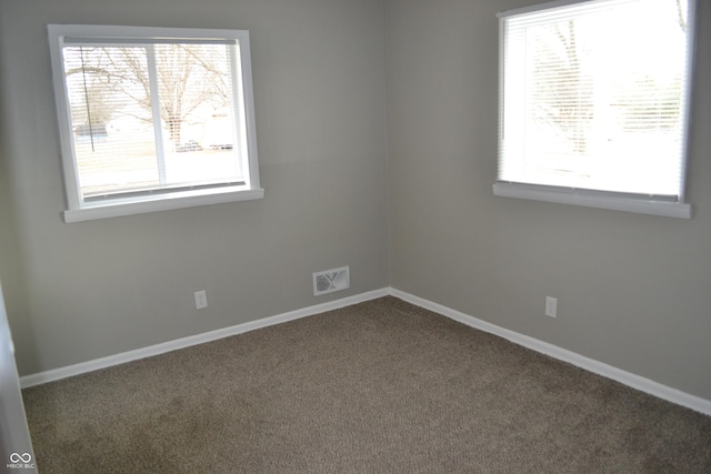 empty room with carpet floors, visible vents, and baseboards