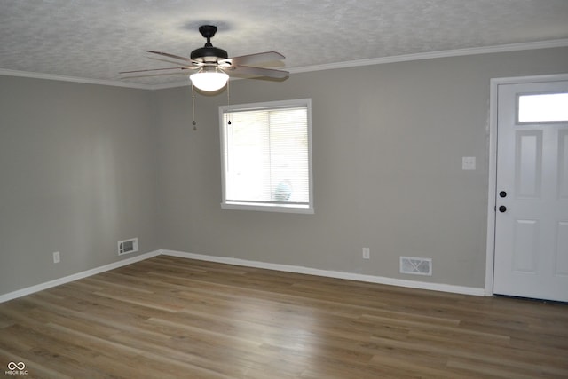 empty room with ornamental molding, wood finished floors, and visible vents