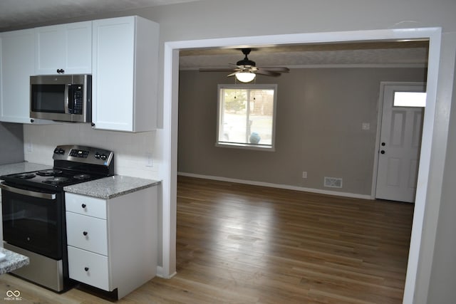 kitchen featuring visible vents, light wood-style flooring, backsplash, appliances with stainless steel finishes, and white cabinetry