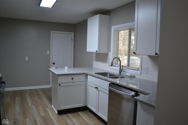 kitchen featuring dishwasher, light stone counters, a sink, and white cabinets