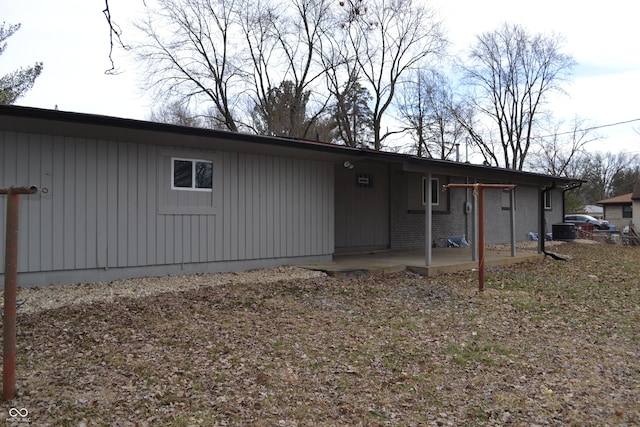 back of house featuring brick siding and a patio