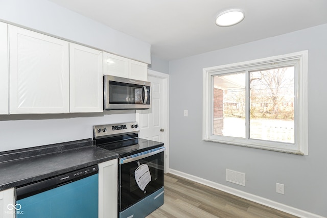 kitchen featuring visible vents, white cabinets, baseboards, dark countertops, and appliances with stainless steel finishes