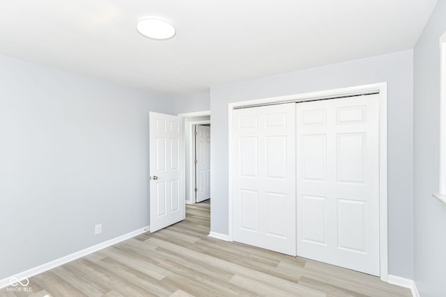 unfurnished bedroom with light wood finished floors, baseboards, and a closet