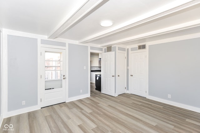 unfurnished room featuring light wood finished floors, beamed ceiling, visible vents, and baseboards