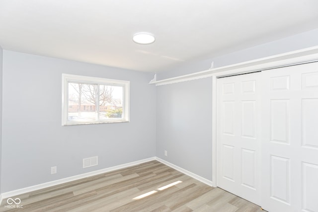 unfurnished bedroom with light wood-style flooring, visible vents, baseboards, and a closet