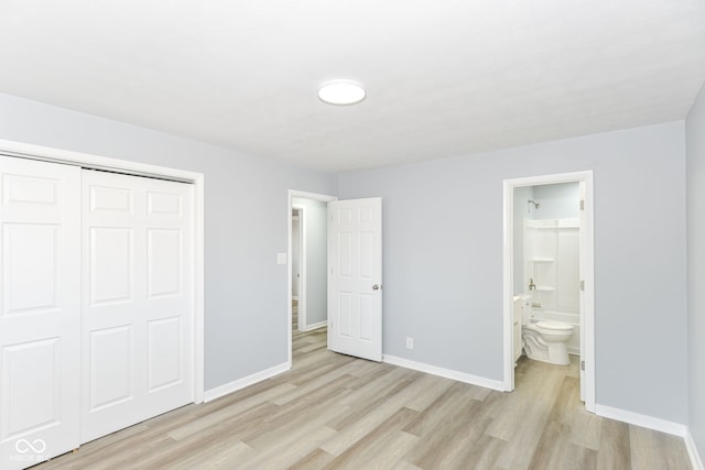 unfurnished bedroom featuring light wood-type flooring, connected bathroom, baseboards, and a closet