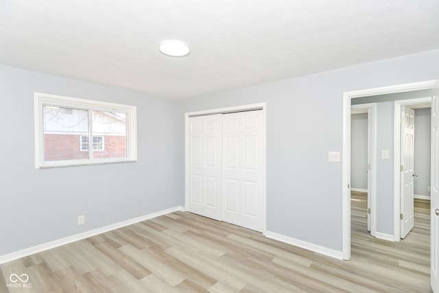 unfurnished bedroom with light wood-style floors, baseboards, and a closet