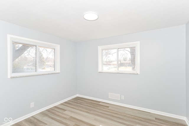 unfurnished room featuring light wood-type flooring, plenty of natural light, and baseboards