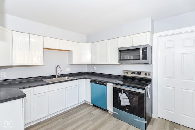 kitchen with white cabinets, light wood-type flooring, stainless steel appliances, and a sink