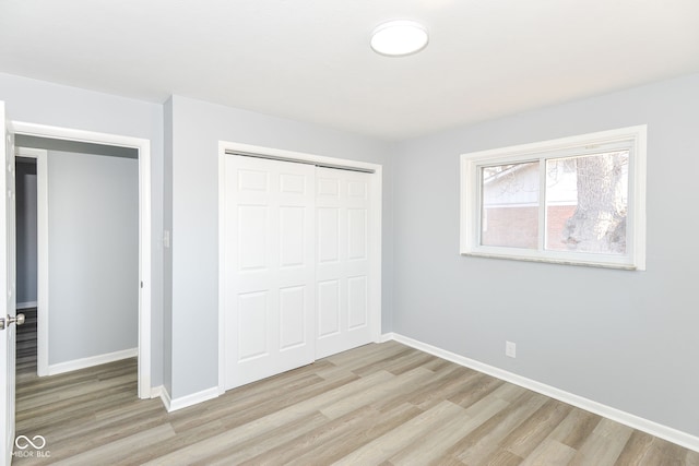 unfurnished bedroom with light wood-style flooring, baseboards, and a closet