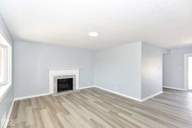 unfurnished living room with light wood-type flooring, a fireplace, and baseboards