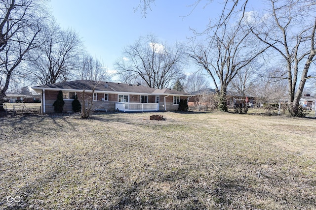 back of house with an outdoor fire pit and a lawn