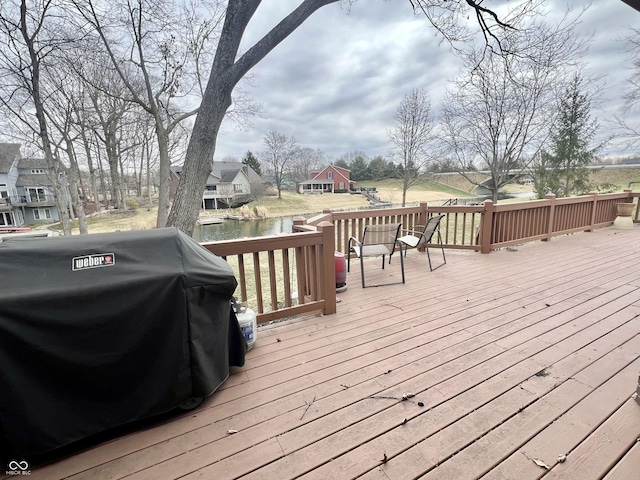 wooden terrace featuring grilling area and a water view