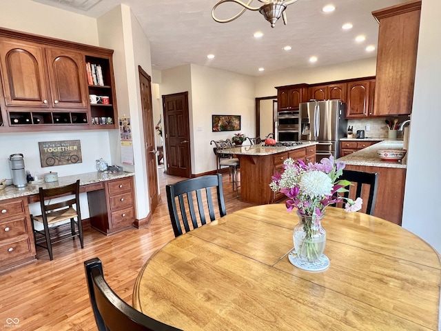 dining room featuring light wood-type flooring, built in desk, baseboards, and recessed lighting